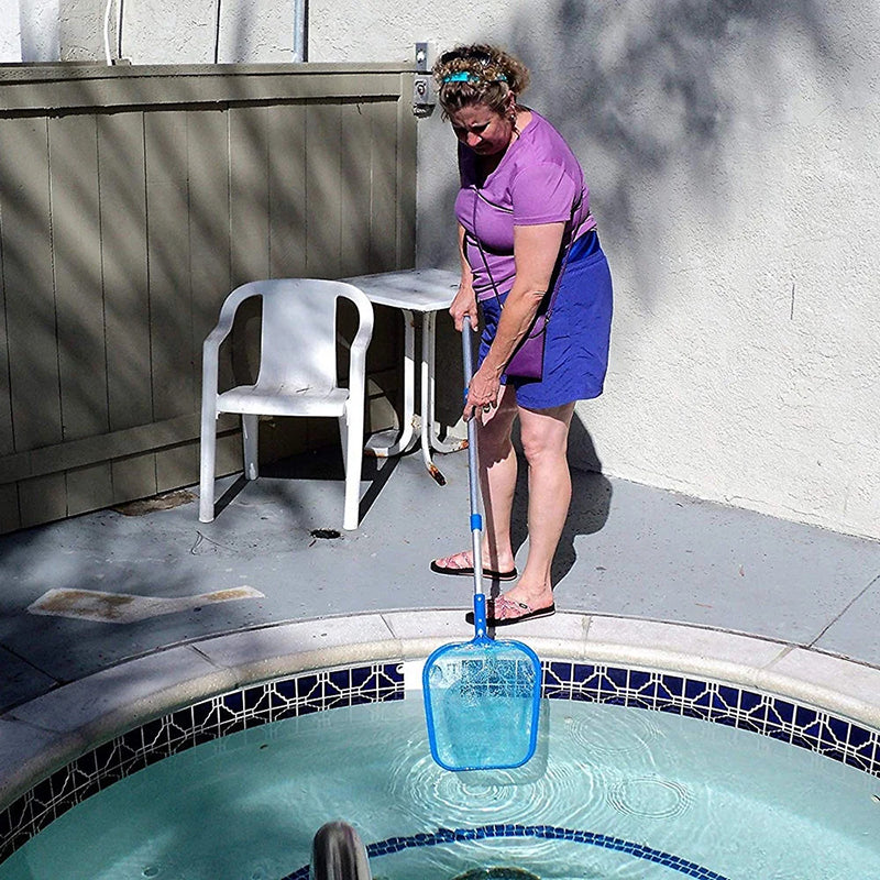 Woman cleaning a pool with a skimmer net on a patio.