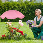 Woman in a garden with a pink umbrella and potted flowers