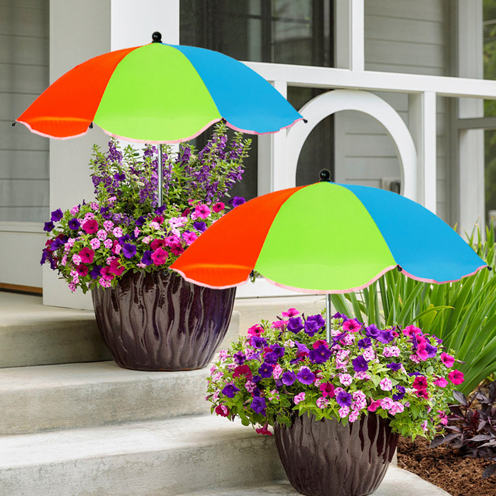 Two potted plants with colorful umbrellas on a porch.