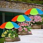 Colorful umbrellas shading potted plants on a stone patio.