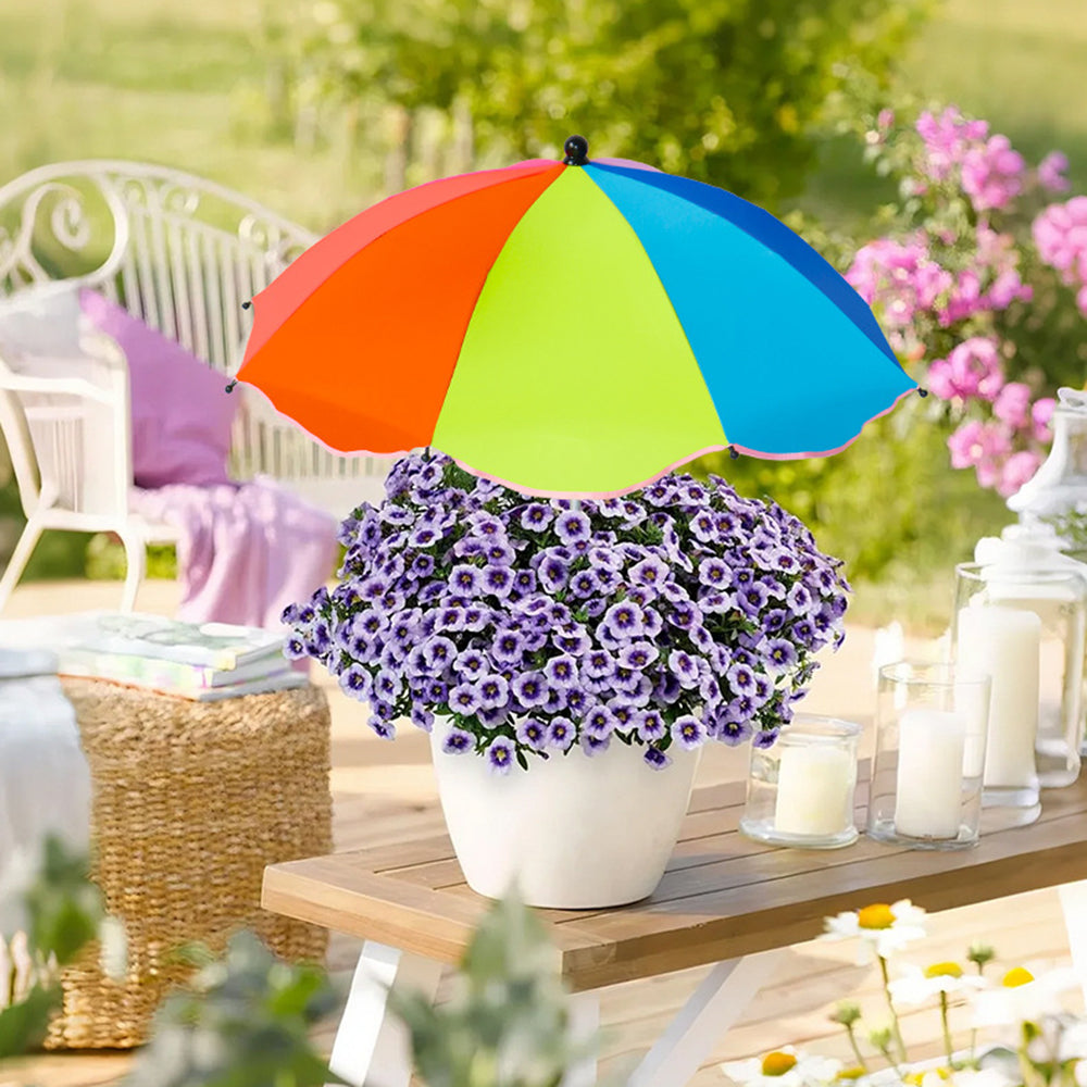 Colorful umbrella over a potted plant on a wooden table outdoors.