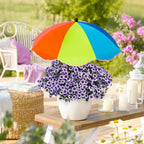 Colorful umbrella over a potted plant on a wooden table outdoors.
