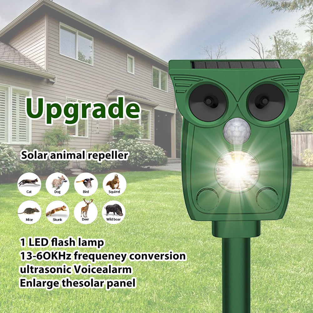 Solar animal repeller in owl design with text on a grassy lawn and house background